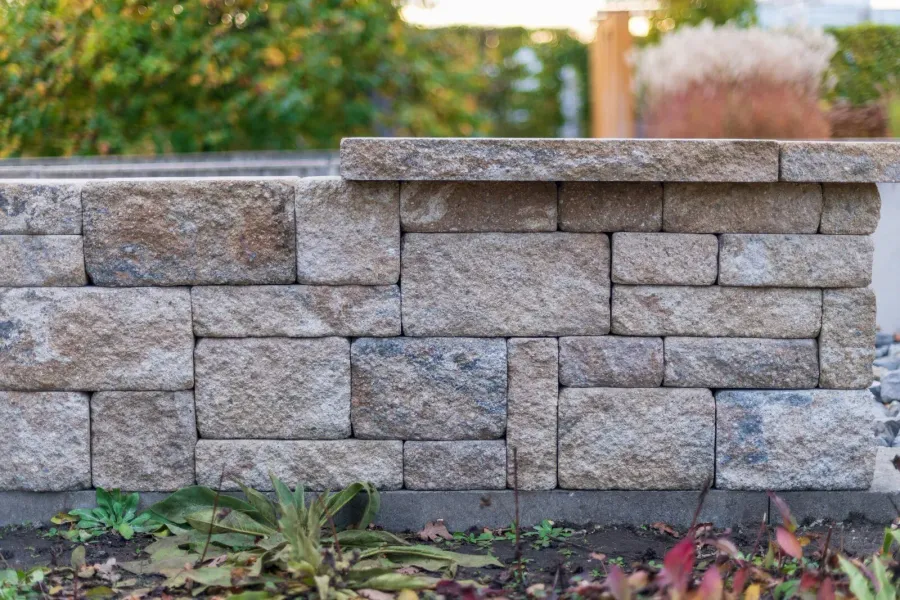 Low segmental block retaining wall with a split-face cap at the edge of a planting bed